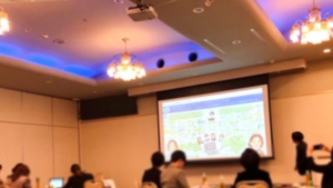 オンライン交流会の会場。スクリーンにグラフィックレコーディングを投影している
