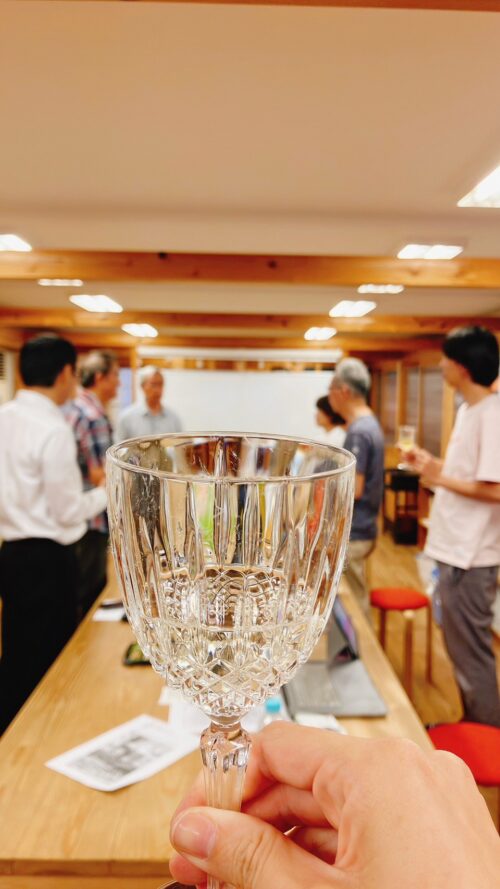 かみかつリアル談義所2023の会場。日本酒のグラスを持っている様子