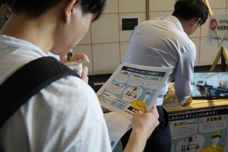ASTERフェス2024 の会場で、学生がプロフィールシートを読んでいる様子