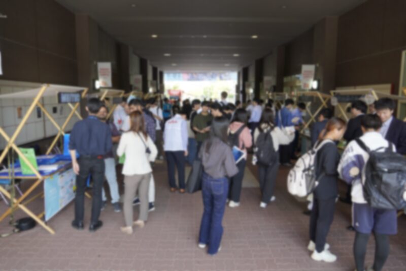 立命館科学技術振興会 ASTERフェス2024 の会場。出展企業のブースが並び、学生が集まっている様子